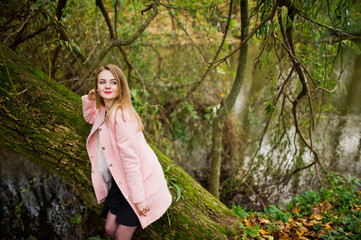 Young blonde girl at pink coat posed on autumn park.