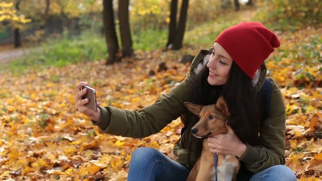 Smiling woman with dog taking selfie in autumn