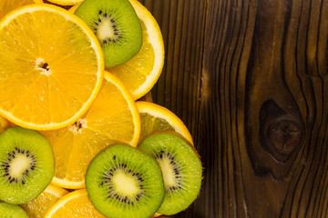 Sliced kiwi fruits and oranges on wooden table