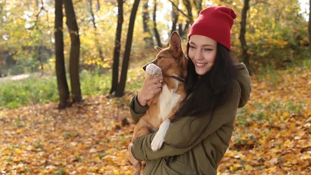 Smiling playful girl with dog on autumn day