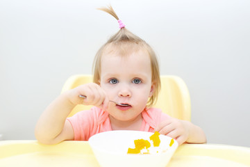Portrait of cute little 1 years girl eating pumpkin at home kitchen