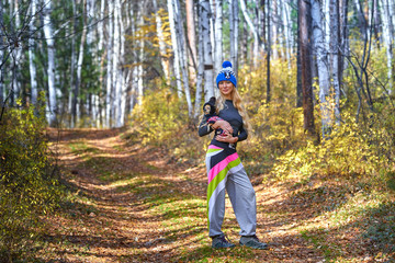 The beautiful blonde in a knitted cap walks with the dog in the autumn wood