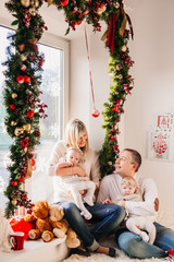 Parents sit with their children before a window decorated for Christmas holidays