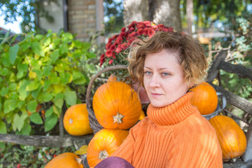 Fototapeta na wymiar Beautiful young woman in orange sweater and orange pumpkins