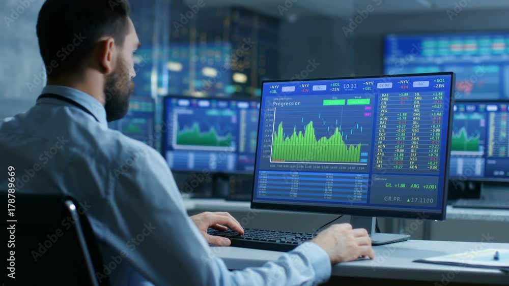 Poster Over the Shoulder View of Stock Market Trader Working on a Computer Showing Stock Ticker Numbers and Graphs.  Shot on RED EPIC-W 8K Helium Cinema Camera.