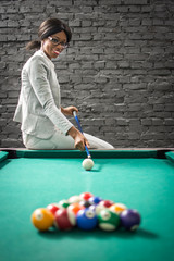 Smiling businesswoman playing billiards.
