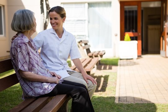 Senior Woman Talking To Doctor While Sitting On Bench