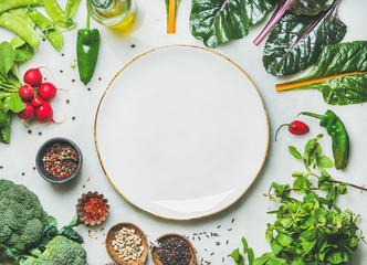 Fresh raw greens, unprocessed vegetables and grains over light grey marble kitchen countertop, wtite plate in center, top view, copy space. Healthy, clean eating, vegan, detox, dieting food concept - obrazy, fototapety, plakaty