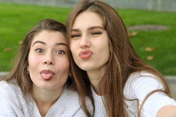 Obraz premium Two friends show their tongue while making a selfie photo
