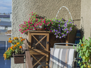 balcony on old prefabricated building  flower box with African Marigold Tagetes and geranium flowers cabinet and arm chair