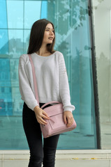 Beautiful brunette with long hair standing with a pink handbag
