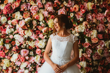 beautiful bride on the background of a wall of flowers