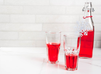 Autumn, winter drinks. Homemade cranberry juice, in a bottle and glasses on white marble table. copy space