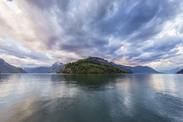 Panorama of the Swiss Alps. Cantons Schwyz, Uri, Obwalden. A grand sunset over the mountains. The clouds over the lake Lucerne are painted in bright halftones.