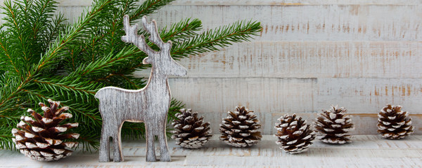 Weihnachten - Holzhintergrund mit Rentier, Tannenzweigen und Tannenzapfen