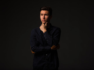 Young pensive man portrait of a confident businessman on a black background. Ideal for banners, registration forms, presentation, landings, presenting concept.