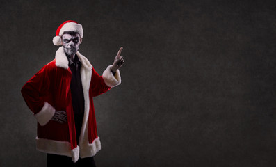 A man in Santa's costume with a makeup skeleton on his face. Christmas. Halloween.