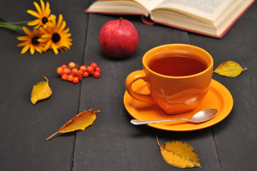 Fototapeta na wymiar Autumn still life cup of tea, flowers and book on the table