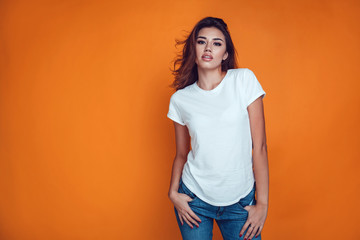 Sexy woman in a white T-shirt on the orange background. Mock-up. - obrazy, fototapety, plakaty
