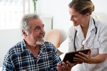 Female doctor showing digital tablet to man in retirement home