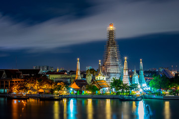 Obraz premium Wat Arun Temple beside Chao Phraya River at twilight time in Bangkok, Thailand. One of the most famous place of Thailand's landmarks. Light reflection on smooth water.