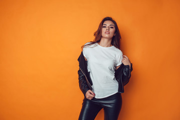 Sexy woman in white t-shirt and jacket on the orange background. Mock-up.