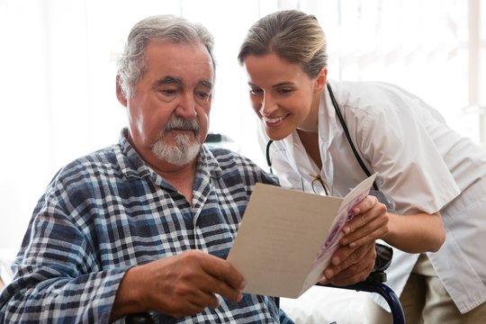 Female doctor showing greeting card to patient sitting on - Powered by Adobe