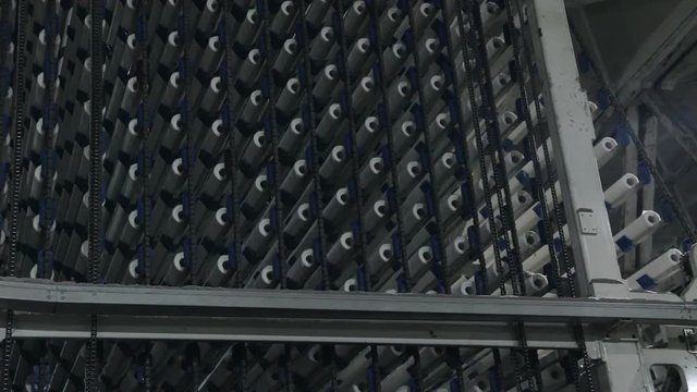 Closeup of moving and rotating core tubes conveyor. Industrial background. Slow pan. Selective focus.