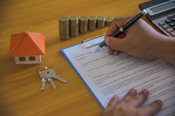 man signing paperwork, new home in background