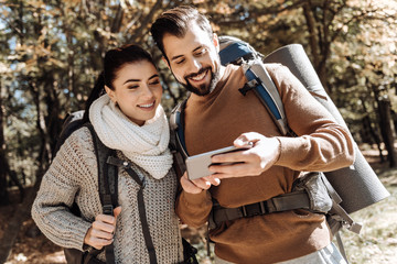 Waist up of positive couple using mobile phone