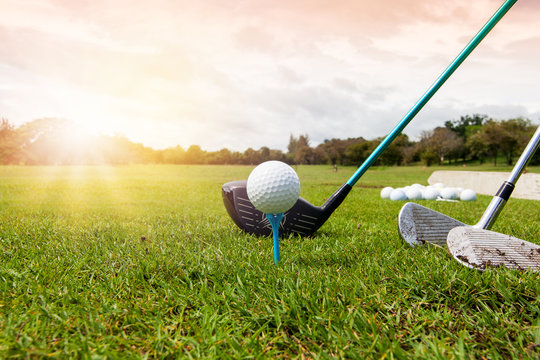 Golf club and golf ball in grass in sunrise.	