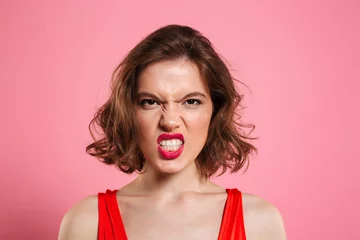 Fotobehang Close-up portrait of angry young woman with red lips looking at camera © Drobot Dean