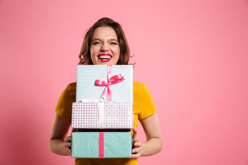 Happy laughing woman with red lips holding bunch of gift boxes, looking at camera