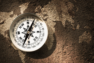 Fototapeta na wymiar Compass on sand with world map, Flat top view, Find the right way for our earth concept