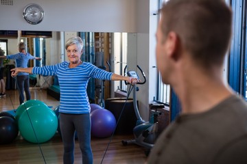 Smiling woman performing exercise with resistance band