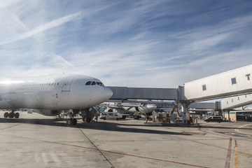 Exterior of a large airport, with vehicles, walkways, airplanes