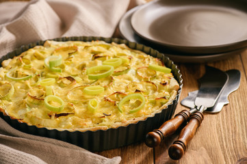 Quiche with leek and cheese on brown background.