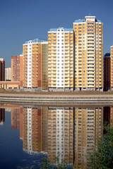 New constructed buildings in the city with reflection in the river on sunny cloudless day