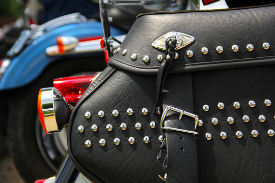 closeup of black leather motorcycle saddlebags with rhinestone studs, cruiser motorcycles in back