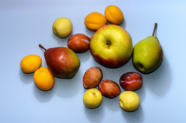 Summer fruits: apples, pears, apricots, plums on a blue table