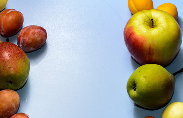 Summer fruits: apples, pears, apricots, plums on a blue table