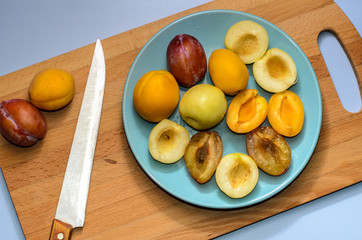 Summer fruits: apples, pears, apricots, plums on a blue plate