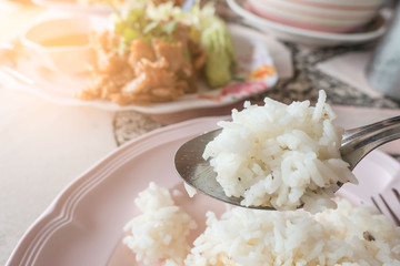 Cooked white rice in the spoon on  table background .