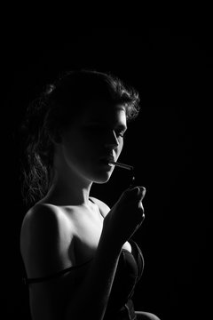 young woman smoking cigarette on black background, monochrome