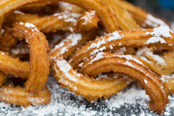 Churros with powdered sugar on plate, closeup