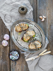 Rustic sandwich set. Sandwiches with smoked meat, cucumber, onion, herbs and spices on a metal dish over rough wood background