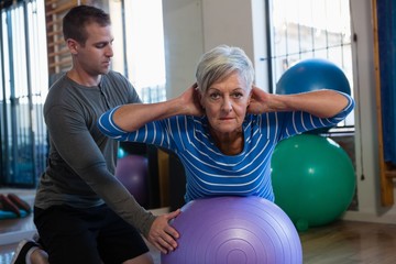 Fototapeta na wymiar Physiotherapist assisting senior woman in performing exercise on