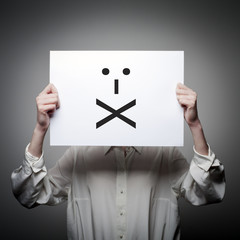 Woman is holding white paper with smile. Lips Sealed. Silence concept.