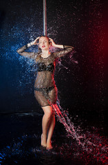 a young beautiful European Ukrainian woman in a photo studio with water is engaged in half-dancing with pole vaults