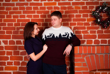 a young man in a New Year's sweater with a deer and a young girl with a New Year's mood